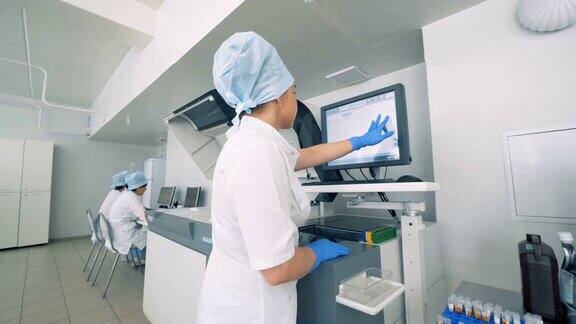 实验室设施与女性实验室专家与触摸屏上的自动制药设备