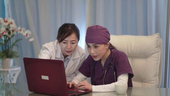 亚洲华人女医生和护士使用笔记本电脑在医生办公室讨论