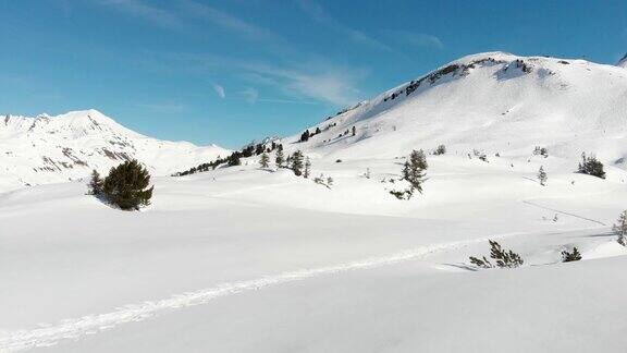 在一个晴朗的日子里晴朗的蓝天在奥地利沃拉尔贝格的一个小城市沃斯无人机低空飞越白雪皑皑的山脉和几条徒步小径