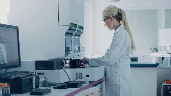 在生物技术实验室女研究科学家分析试管在医疗机器工作与血液遗传物质样本