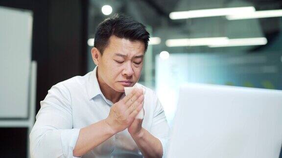 英俊的亚洲男员工患有过敏打喷嚏流鼻涕员工在办公室工作时咳嗽感冒或流感室内