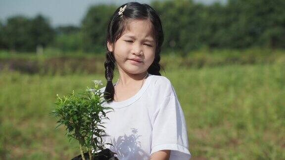一位年轻的亚洲母亲在教她的女儿在丛林里植树志愿者与环境观念