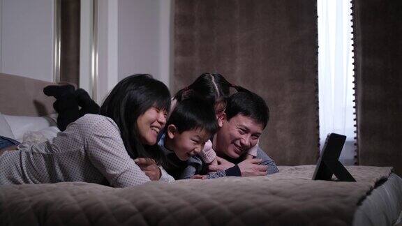 大笑的亚洲家庭在平板电脑上看喜剧