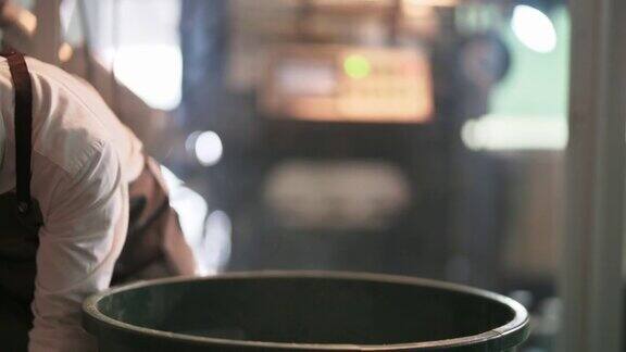 靠近中部的亚洲华人工作高级男子舀生咖啡豆装满桶称重机和混合它在工厂仓库的咖啡烘焙过程中