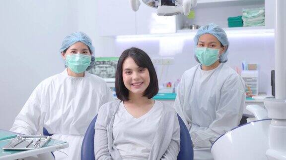 微笑的白人女孩病人的肖像坐在牙科椅子上等待牙医和助手的医疗服务女医生和助理准备提供口腔护理治疗服务