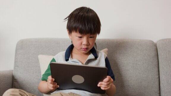 亚洲男孩拿着数码平板电脑玩游戏
