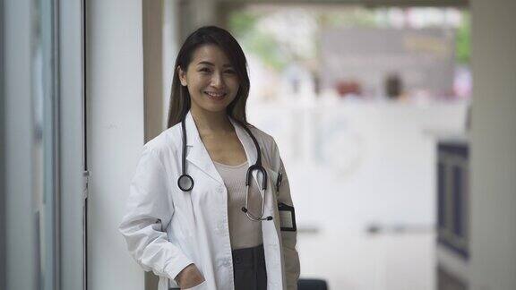 亚洲华裔女医生站在医生办公室前微笑着看着镜头