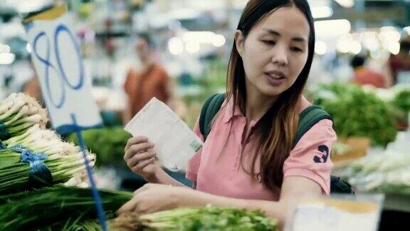 年轻女子在超市的菜区挑选蔬菜