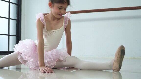 平移视图:芭蕾舞学生坐着伸展她的腿