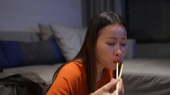 亚洲女人晚餐吃中国面条看电视上的电影