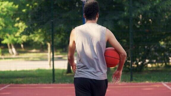 后景的年轻人走在篮球场与球腋下运动