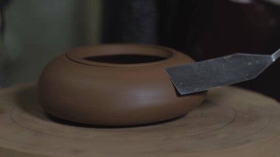 陶工以宜兴陶土为原料用木轴上的金属铲加工茶壶茶道用手工陶壶褐色陶器茶壶4k的视频59.94帧秒