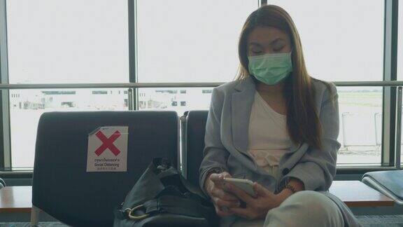 东南亚商人在国际机场等待她的航班和使用智能手机