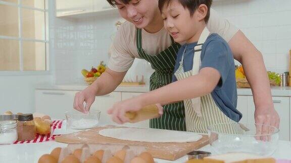 快乐的年轻亚洲父亲和儿子在家里的厨房里做饭