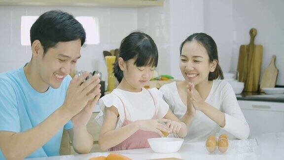 微笑的亚洲父亲母亲和女儿喜欢在厨房一起准备健康的晚餐母亲教女儿做饭