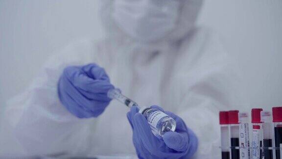 (特写)实验室中穿着个人防护服的医生或科学家将疫苗注入注射器