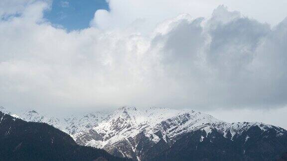 在印度喜马偕尔邦的马纳里寒冷的冬天早晨云在积雪覆盖的山上移动的4K时间推移白雪皑皑的喜马拉雅山和多云的天空景观自然背景