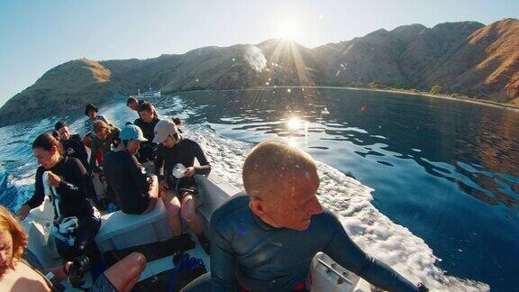 一群穿着潜水服的自由潜水者坐在小船上在日出时前往潜水点科莫多国家公园印度尼西亚