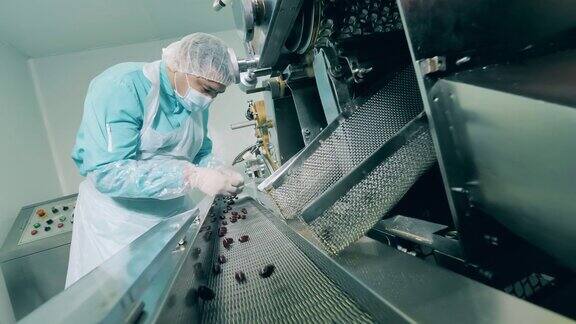 男性药剂师在实验室检查黑色胶囊在一个现代化的制药设施的药品生产线