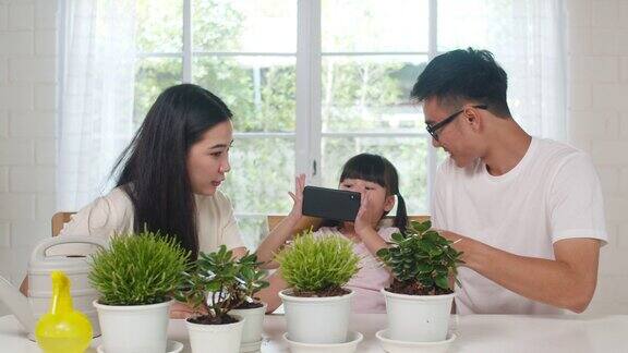 快乐快乐的亚洲家庭爸爸妈妈和女儿用智能手机在花园里的植物拍照