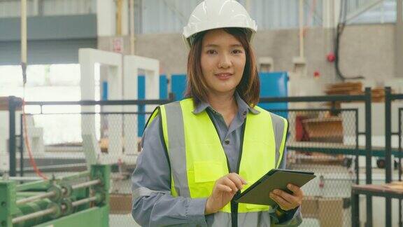 专业的亚洲女性工业工程师在制造工厂微笑着看着相机在制造厂或生产厂工作