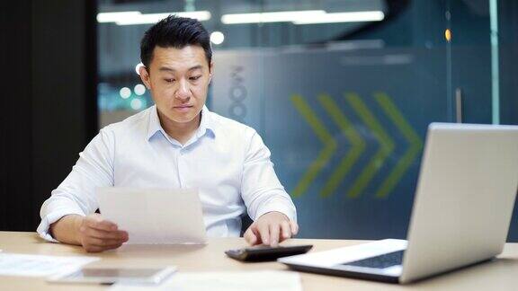 繁忙的员工会计簿记工作在办公室工作场所计算利润税文书日常工作集中亚洲男性企业家经理分析统计在纸质报告