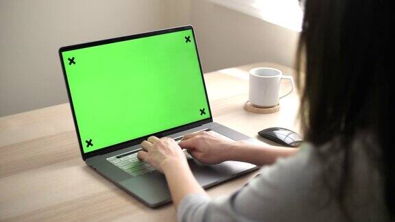 一个女人在用绿色屏幕的笔记本电脑