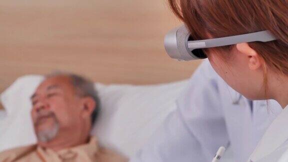 后视图近距离女医生经验丰富的执业医师佩戴虚拟现实头戴式耳机分析诊断亚洲患者老年男性躺在医疗诊所的床上虚拟现实