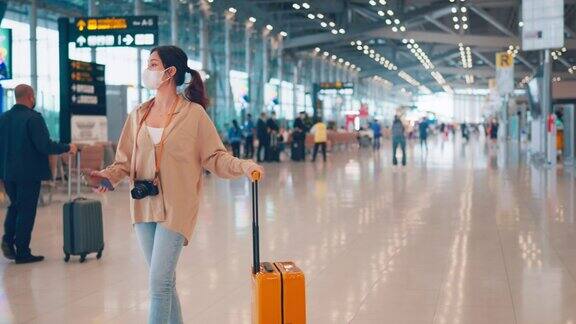 在机场候机楼一名女士一边拿着行李箱和相机一边使用智能手机查看手机旅游旅程旅行概念