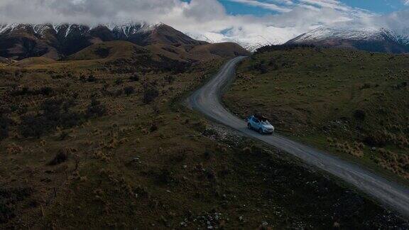 鸟瞰图SUV驾驶在沙漠向雪山山峰在新西兰