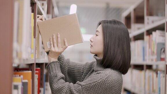 亚洲女学生在图书馆的书架上挑选书籍