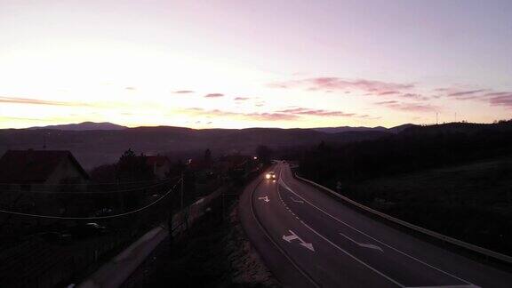 夜骑鸟瞰图无人机在道路上方拍摄夕阳在远处