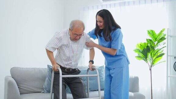 亚洲老年男性患者与护工进行物理治疗有魅力的专业护工女性帮助和支持年长的成熟男性在养老院用助步器练习慢慢走路