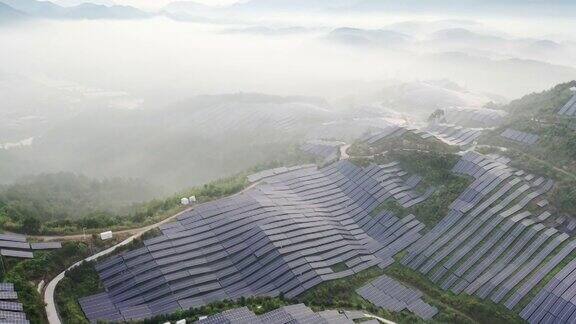 在晨雾中鸟瞰山坡上起伏的太阳能发电厂