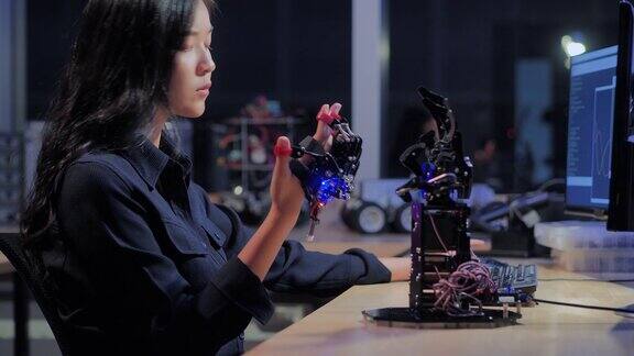 一个未来主义的假肢机器人手臂由一个十几岁的女孩开发工程师在一个研究实验室工作到深夜手臂移动手指教育、技术、团队合作、后期工作、科学人本理念教育的主题4.0行业
