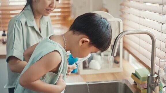 亚洲男孩在母亲的帮助下用生理盐水注射器冲洗鼻腔