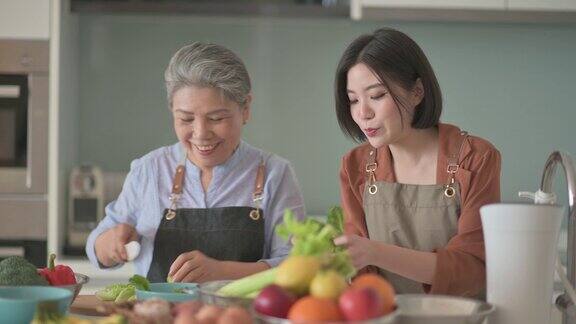 亚洲华人美丽的女人和她的母亲准备做饭为家人在厨房柜台