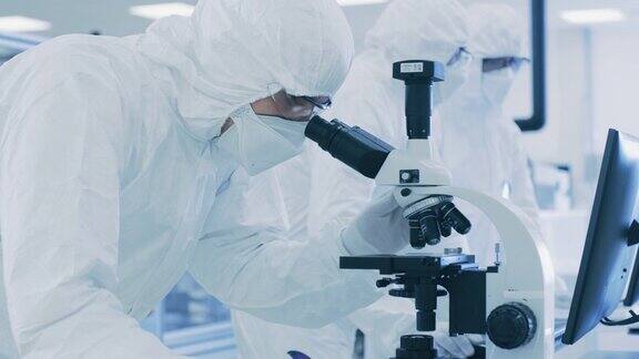 在实验室科学家穿着防护服做研究使用显微镜