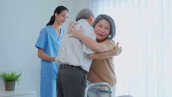 亚洲老年男性正在与护理人员和他的妻子进行物理治疗有吸引力的专家护理妇女帮助和支持年长的成熟的男人病人实践行走缓慢与步行者在养老院照顾