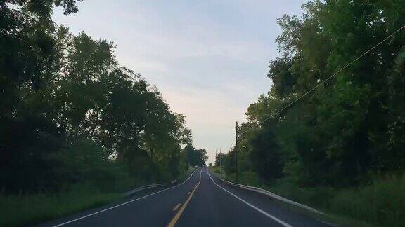 在日落时分沿着宾夕法尼亚州巴洛附近的一条林荫大道行驶