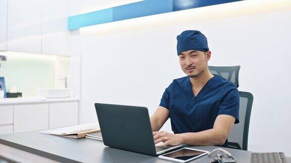 亚裔华人男性医生在医生的办公室里微笑着看着镜头
