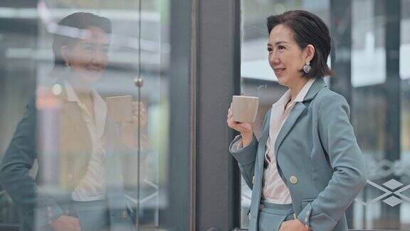 成功的亚裔中国女性首席执行官高级管理人员看着别处微笑站在窗口
