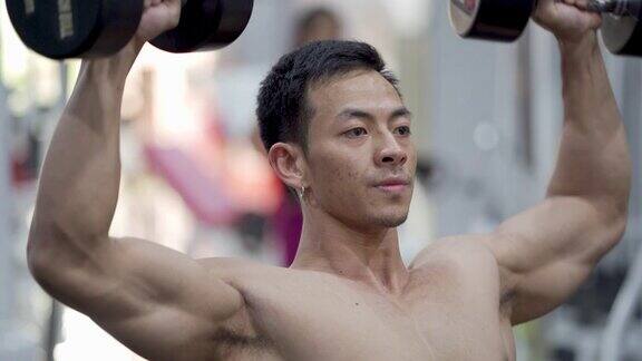 亚洲年轻人在健身房锻炼手臂和肩膀正面视图