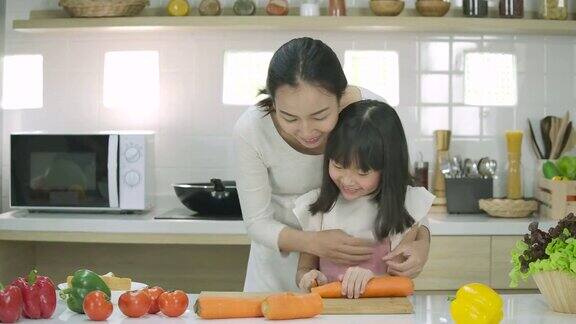 微笑着的怀孕母亲和女儿喜欢在厨房里一起准备健康的晚餐母亲教女儿做饭