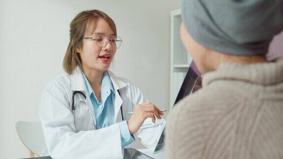年轻的亚洲女性在健康诊所为患有癌症的女性病人看病时医生们的医疗结果