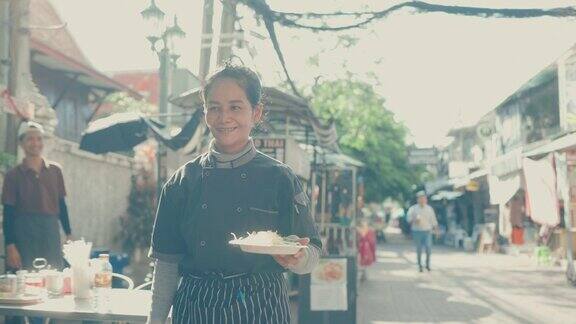 泰国饮食文化:女厨师在市场准备传统泰式炒粉