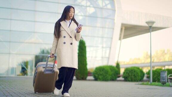 亚洲女旅游商人走手提箱从航站楼机场背景现代城市火车站城市街道