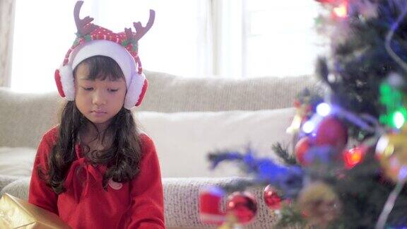 圣诞节打开礼物前小女孩兴奋地摇晃着礼物