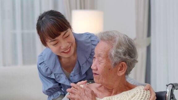 83岁的亚洲老年妇女坐在轮椅上与亚洲年轻女性进行家庭护理而她触摸亚洲老年祖母病人的肩膀帮助表达同理心鼓励告诉诊断在医疗访问的亚洲年轻女性
