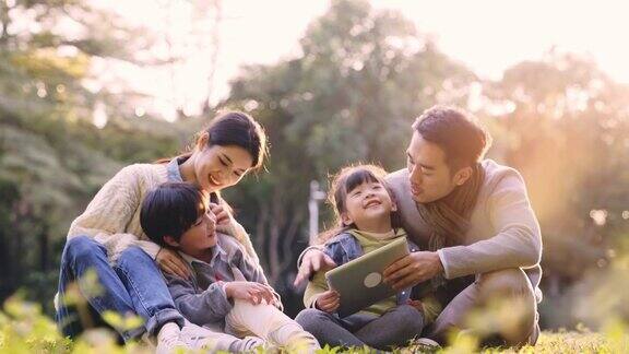 年轻的亚洲家庭在公园草地上放松